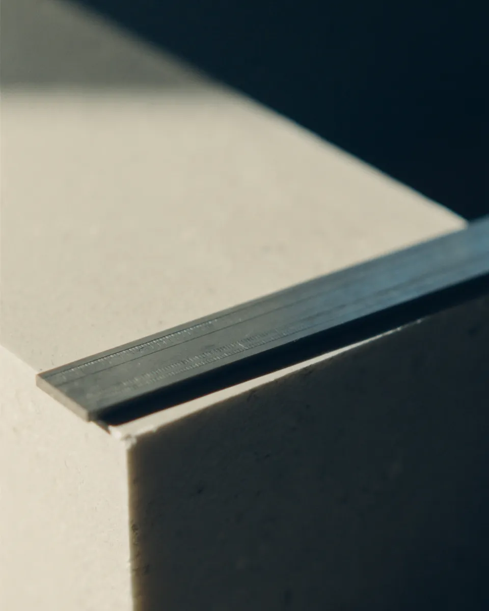 A ground steel rule with fine ticks, lying across a pale limestone slab.