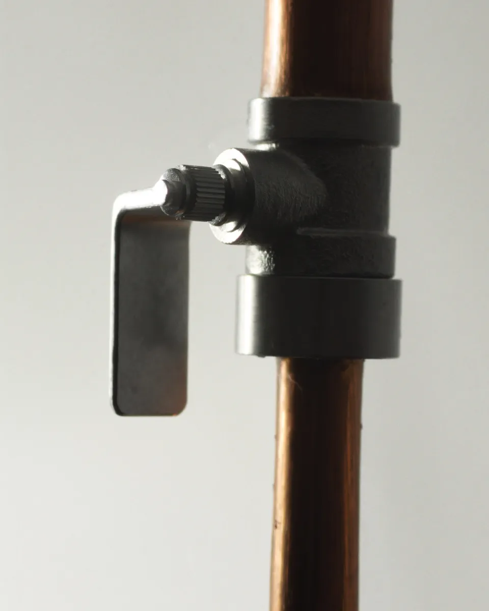 A steel shut-off valve on a copper pipe, its lever closed.